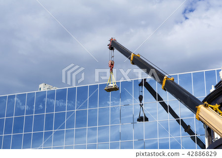 crane lifts the load against the mirror wall 42886829