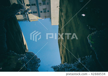 Dilapidated dirty building reflected on a puddle. 42888534