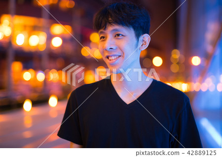 Happy Asian Man Thinking Outdoors At Night Happy Asian Man Thinking Outdoors At Night 42889125