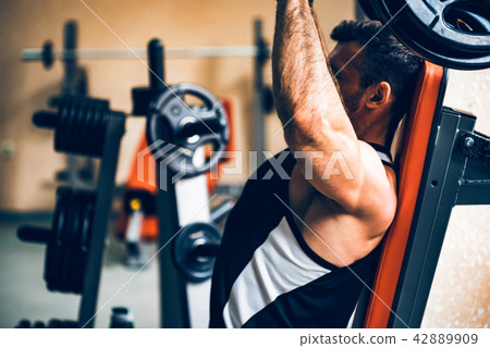 Athlete does deltoid exercises on hammer machine Athlete does deltoid exercises on hammer machine 42889909
