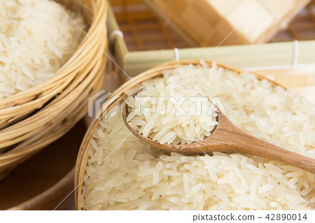 Raw and uncooked rice in wooden spoon. Raw and uncooked rice in wooden spoon. 42890014