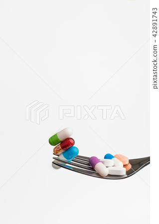 Many capsules medicine on fork 42891743