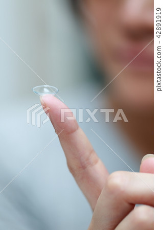 戴隱形眼鏡的女性手指 42891919