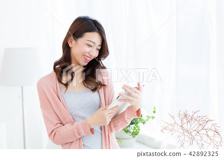 觀看一種片劑的婦女在屋子裡 觀看一種片劑的婦女在屋子裡 42892325
