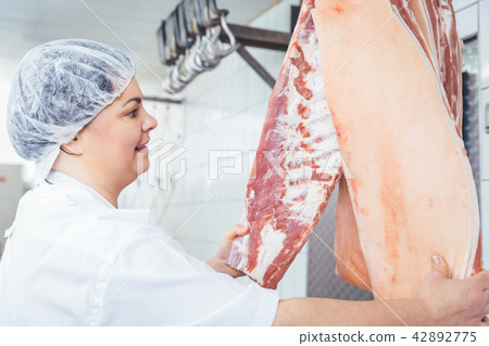 Butcher woman cutting meat for further use 42892775