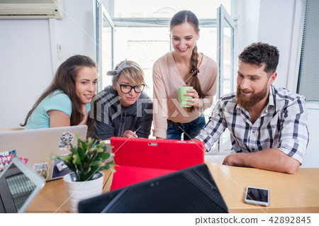 Four co-workers watching a business presentation in a modern shared office space 42892845