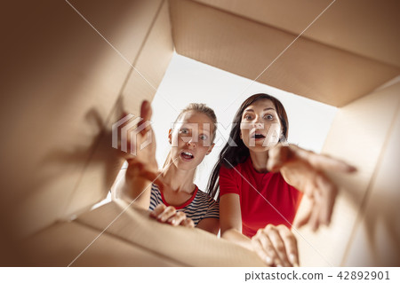 Women unpacking and opening carton box and looking inside 42892901
