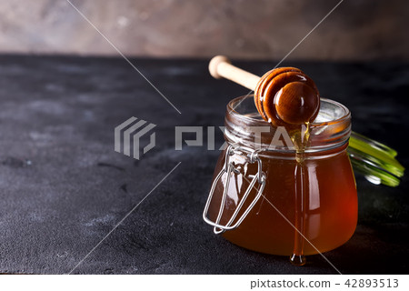 Honey dripping from a dipper into the jar full Honey dripping from a dipper into the jar full 42893513