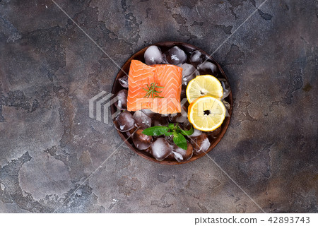Salmon steaks on ice with lemon slice on wooden Salmon steaks on ice with lemon slice on wooden 42893743