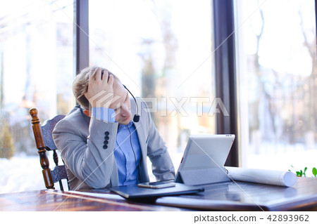 Young draftsman talking with client by tablet, headset phones an Young draftsman talking with client by tablet, headset phones an 42893962