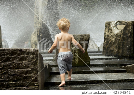 Cute toddler playing in the city fountain. Back view 42894841