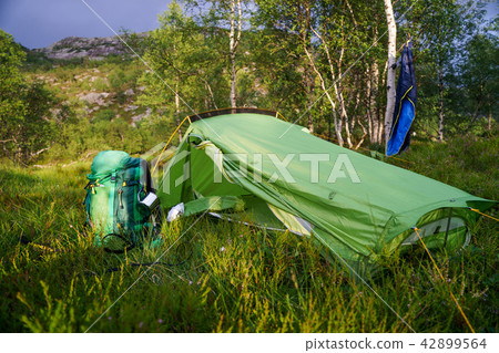 The tent stands in a clearing in the field with trees 42899564