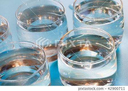 Glass of water on pastel blue. Close up. Glass of water on pastel blue. Close up. 42900711