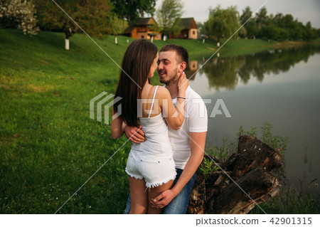 Dating in park. Love couple standing together on grass near the lake. Romance and love Dating in park. Love couple standing together on grass near the lake. Romance and love 42901315