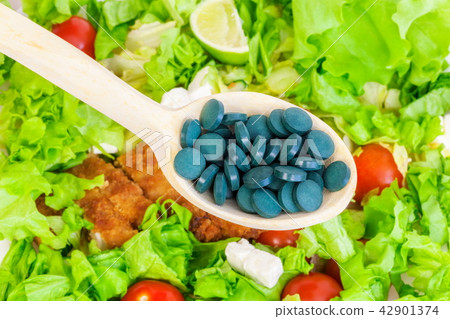 Spirulina tablets in wooden spoon.Nutrient rich fo Spirulina tablets in wooden spoon.Nutrient rich fo 42901374
