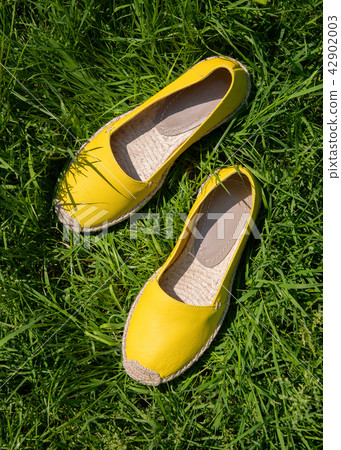 Yellow fashionable espadrilles on green grass Yellow fashionable espadrilles on green grass 42902003