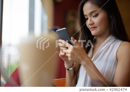 Young beautiful Asian businesswoman relaxing at the coffee shop Young beautiful Asian businesswoman relaxing at the coffee shop 42902474