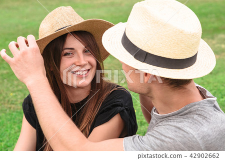 Young fit couple sit together wearing straw hats Young fit couple sit together wearing straw hats 42902662