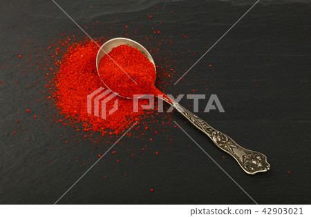 Metal spoon full of red hot chili pepper on black Metal spoon full of red hot chili pepper on black 42903021
