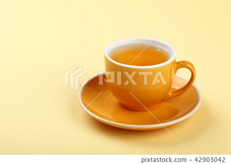 Yellow cup of green oolong tea on saucer Yellow cup of green oolong tea on saucer 42903042