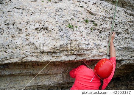 Photo from back of woman in helmet clambering over rock Photo from back of woman in helmet clambering over rock 42903387