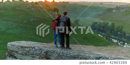 Photo from back of hugging young couple of tourists on mountain 42903389