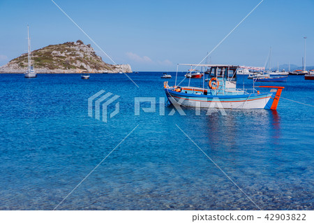 Colorful greek Mediterranean fishing boat at the calm clear blue sea water bay on early summer 42903822