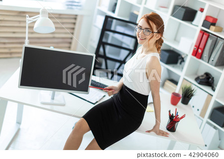 A beautiful young girl in the office sat down on the table and was holding a red pencil in her hand A beautiful young girl in the office sat down on the table and was holding a red pencil in her hand 42904060