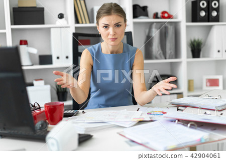 A young girl sits at a table in her office and spread her arms out to the sides. A young girl sits at a table in her office and spread her arms out to the sides. 42904061