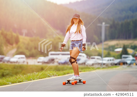 Young girl longboarding downhill on hillside road Young girl longboarding downhill on hillside road 42904511