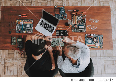 Two Men with Motherboars and Tools on Wooden Table 42904817