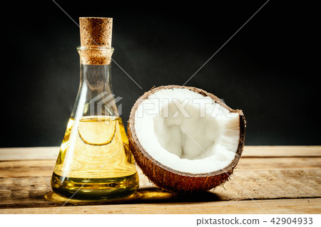 coconuts and a bottle of oil on a wooden table on a black background coconuts and a bottle of oil on a wooden table on a black background 42904933