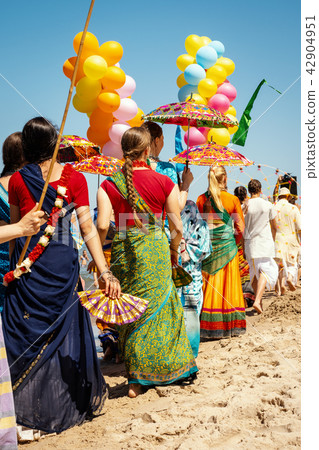 hare krishna women in colorful dresses are walking on the beach 42904951