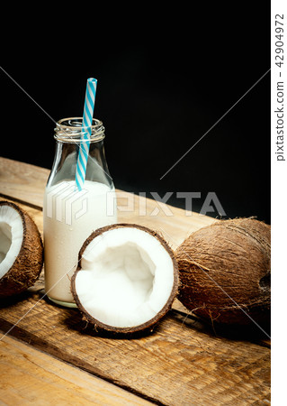 coconuts and bottle of milk on a wooden table on a black background 42904972
