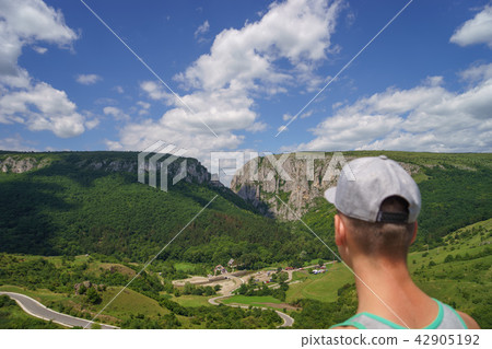 Summer hiking in the mountains. Young tourist man in a cap looking on mountain 42905192
