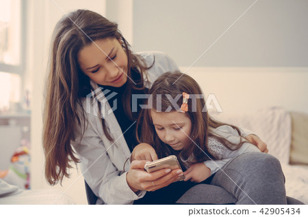 Mom and daughter are looking at the smartphone Mom and daughter are looking at the smartphone 42905434