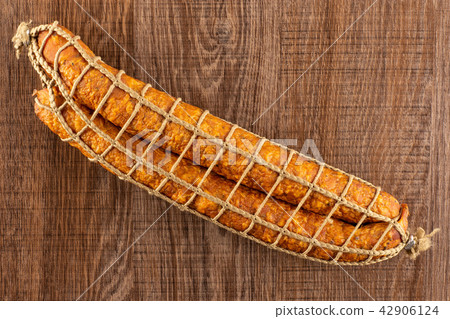 Dry smoked ham sausage on brown wood Dry smoked ham sausage on brown wood 42906124