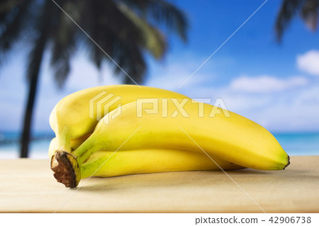 Fresh yellow banana with palm beach behind Fresh yellow banana with palm beach behind 42906738