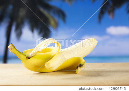 Fresh yellow banana with palm beach behind 42906743