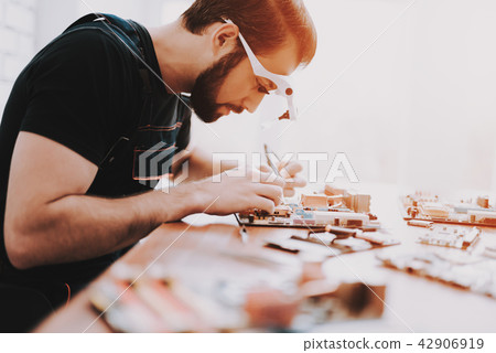 Young Bearded Man Repairing Motherboard from PC. Young Bearded Man Repairing Motherboard from PC. 42906919
