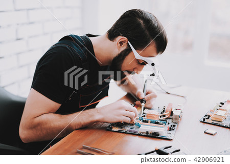 Young Bearded Man Repairing Motherboard from PC. Young Bearded Man Repairing Motherboard from PC. 42906921