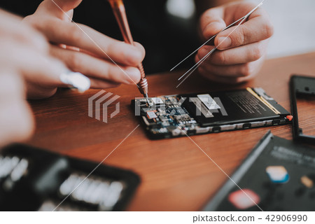 Close up. Young Man Repairing Mobile Phone on Desk 42906990
