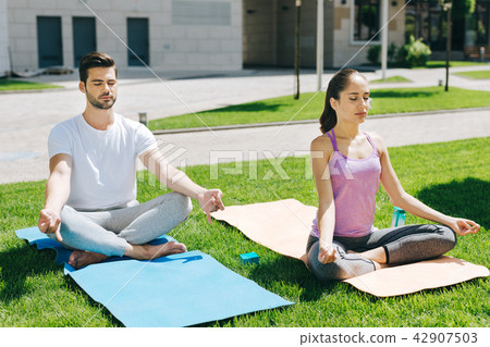Peaceful nice people sitting on yoga mats 42907503