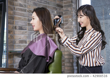 Hairdresser styling woman's hair in a salon. Korean beauty stock photo. 075 42908516