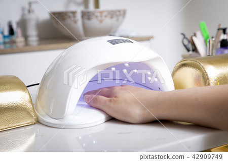 Nail salon woman hands treatment. Nail saloon woman painting color nail polish in hands stock photo. 047 42909749