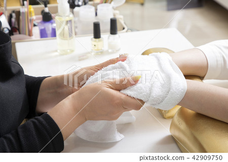 Nail salon woman hands treatment. Nail saloon woman painting color nail polish in hands stock photo. 043 42909750