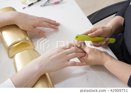 Nail salon woman hands treatment. Nail saloon woman painting color nail polish in hands stock photo. 039 42909751