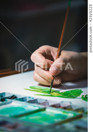 Woman hand using brush to paint on white paper 42920228