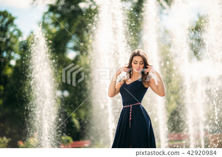 A girl is walking around the city, near a large fountain. Sunny day. Summer A girl is walking around the city, near a large fountain. Sunny day. Summer 42920984