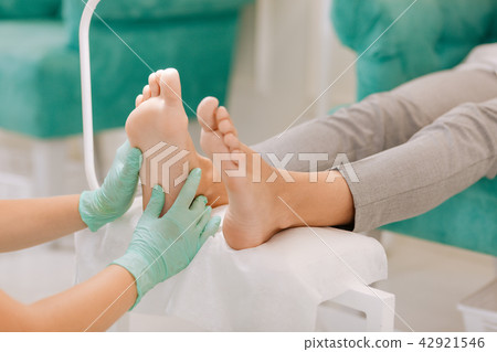 Chiropodist wearing gloves making acupressure for woman Chiropodist wearing gloves making acupressure for woman 42921546
